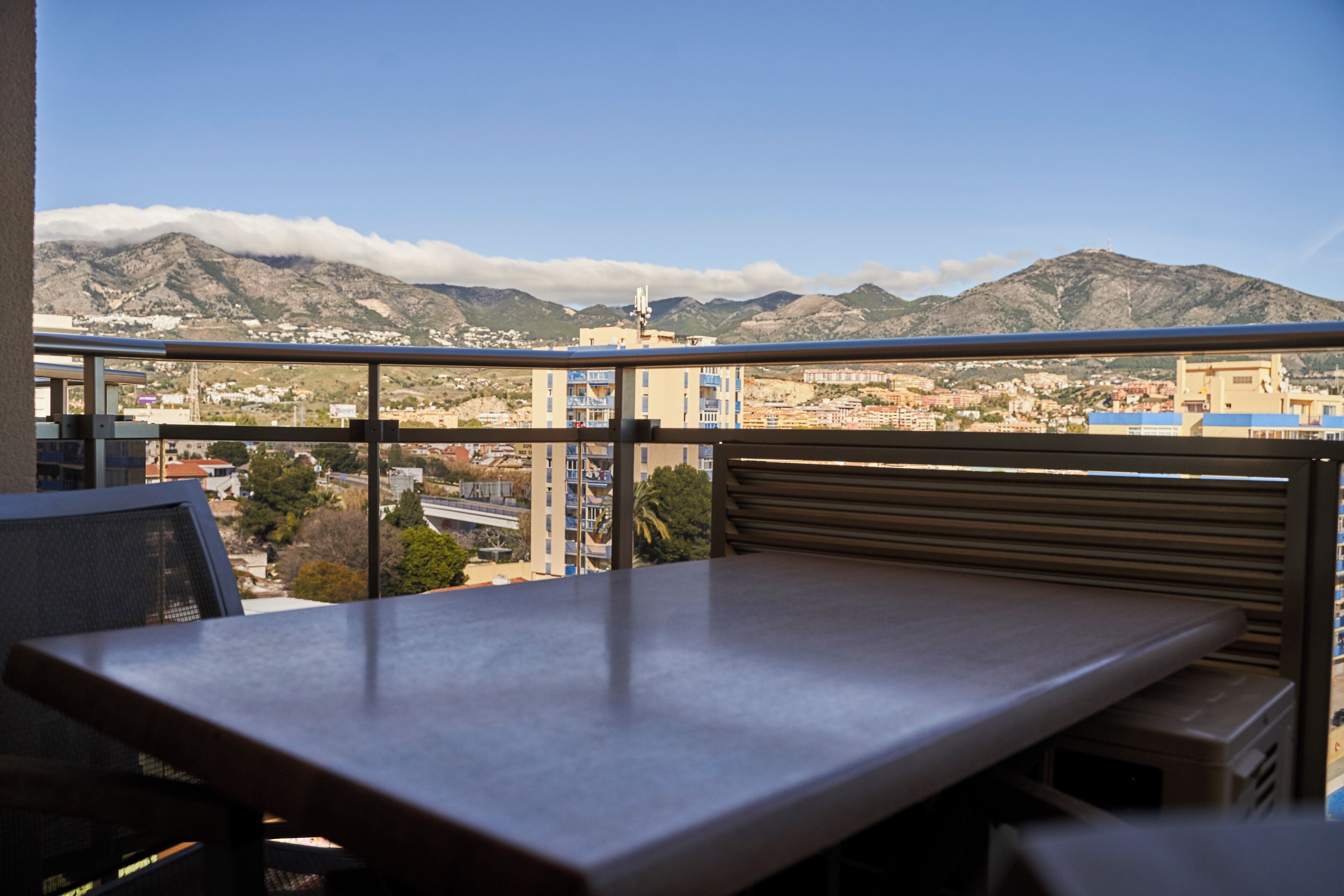 A balcony with a view of mountains and a cityscape.
