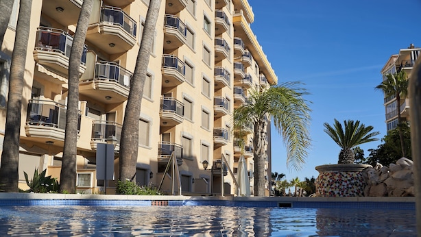 A hotel with multiple balconies, a swimming pool, and palm trees. - Mediterraneo Real Apartamentos Turísticos (Fuengirola)
