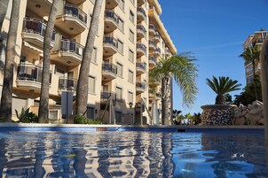 Una piscina al aire libre, sombrillas, sillones reclinables de piscina