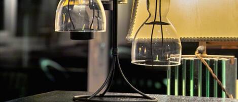 Une table surmontée de deux lampes en verre transparent, posée sur une surface sombre, peut-être dans une bibliothèque ou un espace de travail.