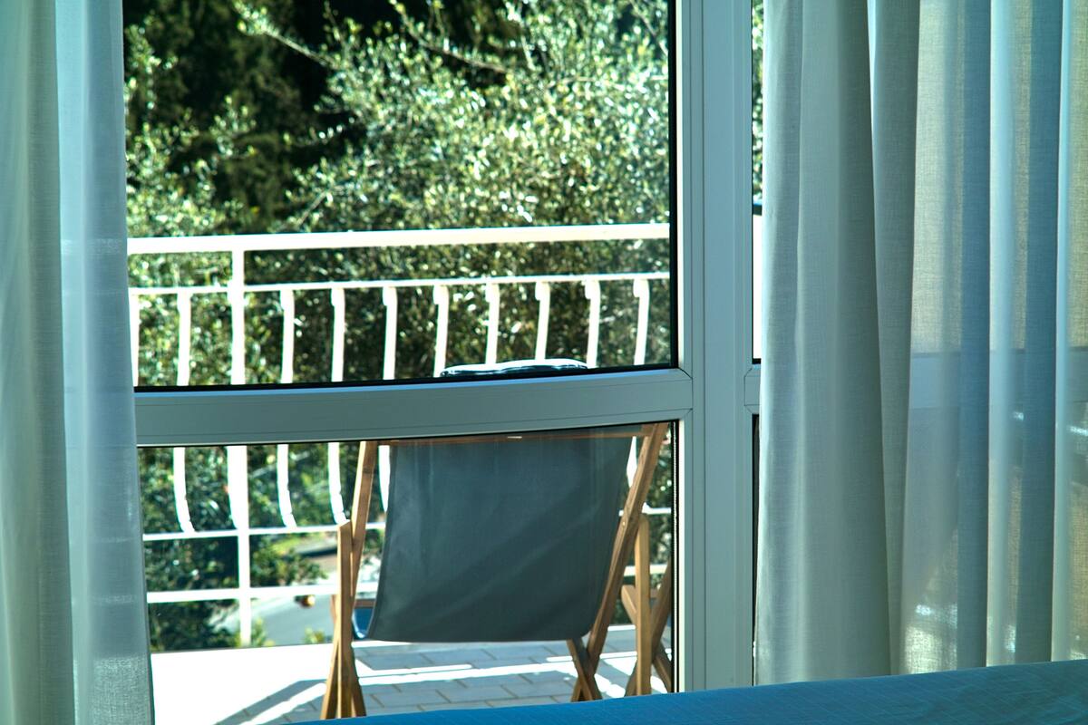 Ein Balkon mit weißer Reling und einem blauen Stuhl.
