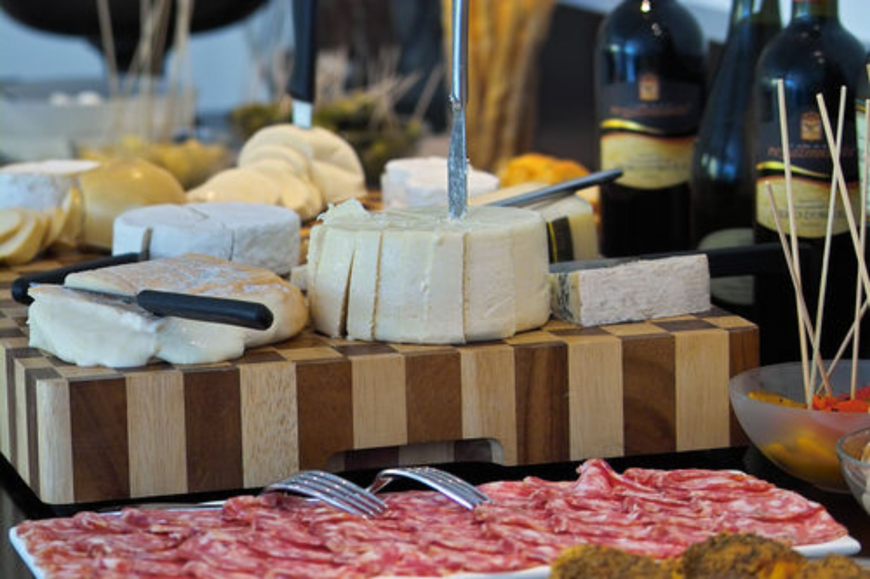 Tagliere con formaggi e salumi assortiti, un coltello e una bottiglia di vino.