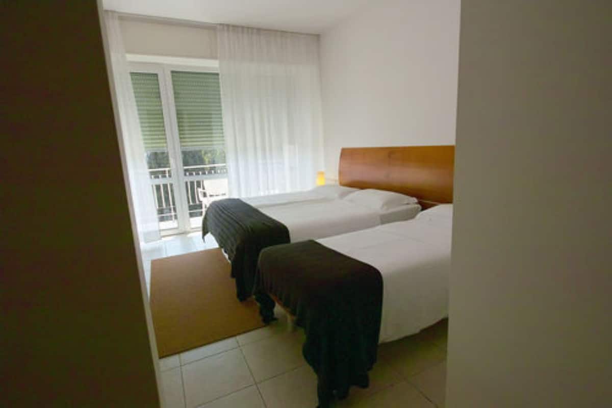 Ein Hotelzimmer mit zwei Betten, einem Balkon und Blick nach außen.