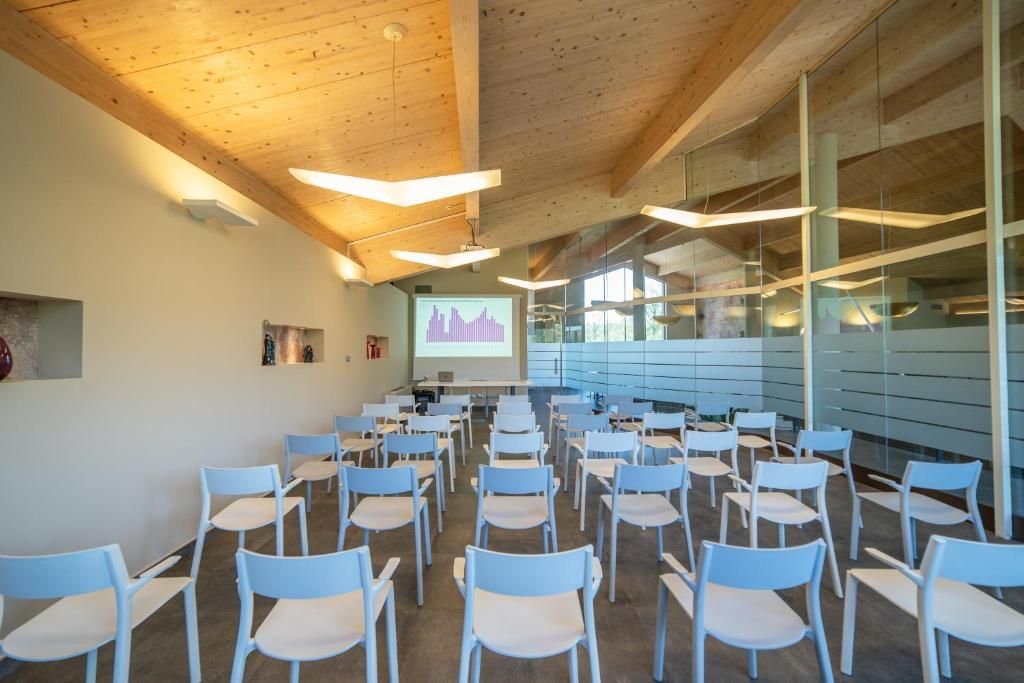 A conference room with rows of chairs, a projector screen, and a presentation.