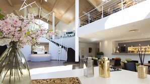 A spacious, multi-level interior with a modern design, featuring a staircase, a reception area, and a bar/lounge area. - Hotel Capolago (Varese)