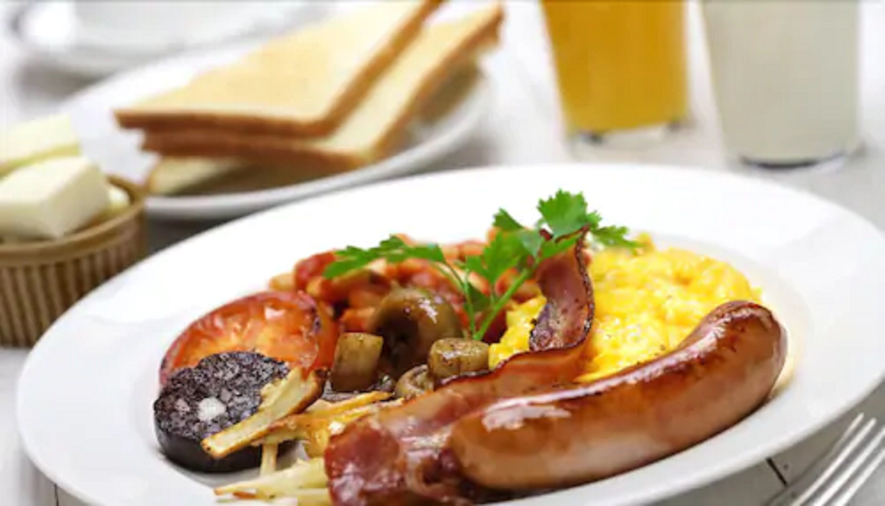 A plate of breakfast with eggs, sausage, and tomatoes.