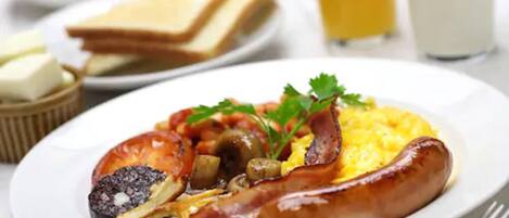 Un plato de desayuno con huevos, salchicha y tomates.