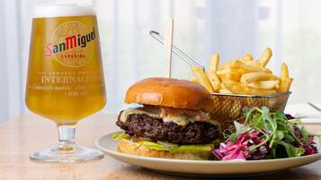 A meal with a burger, fries, and a beer glass on a wooden table.