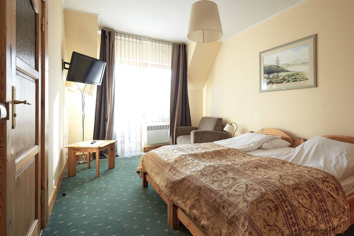 Habitación de hotel con cama, escritorio, silla, televisión y un cuadro en la pared.