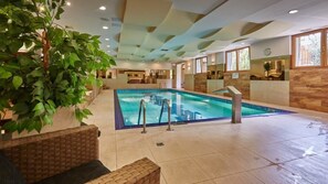 A spacious indoor swimming pool with clear water, surrounded by a tiled floor and wooden walls. - Skalny (Zakopane)