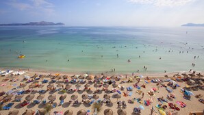 A beach with numerous umbrellas and sun loungers, a clear sky, and calm waters. - Hotel JS Can Picafort (Santa Margalida)
