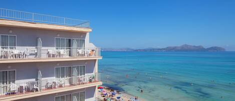 Un hotel de varios pisos con balcones que dan a la playa.