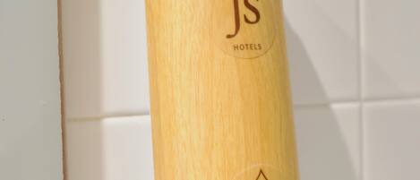 A cylindrical soap dispenser with the logo 'Js Hotels' and the text 'Bathlia Hand soap' on a white tiled wall.