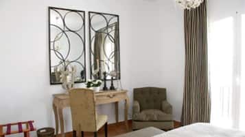 A bedroom with a bed, a desk with a chair, a large mirror, and a window with curtains.