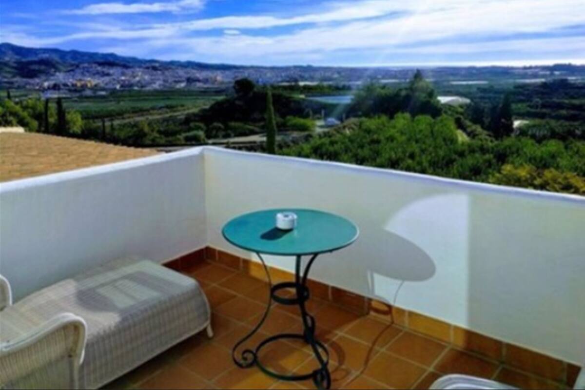A balcony with a view of a cityscape, a small round table with a chair, and a sofa.