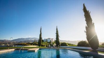 Una piscina al aire libre de temporada, sombrillas