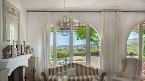 Une pièce avec un canapé, des fauteuils, une table décorée de bougies et une vue sur l’extérieur.