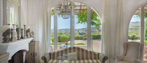 Una habitación con sofá, sillones, una mesa con velas y vistas al exterior.
