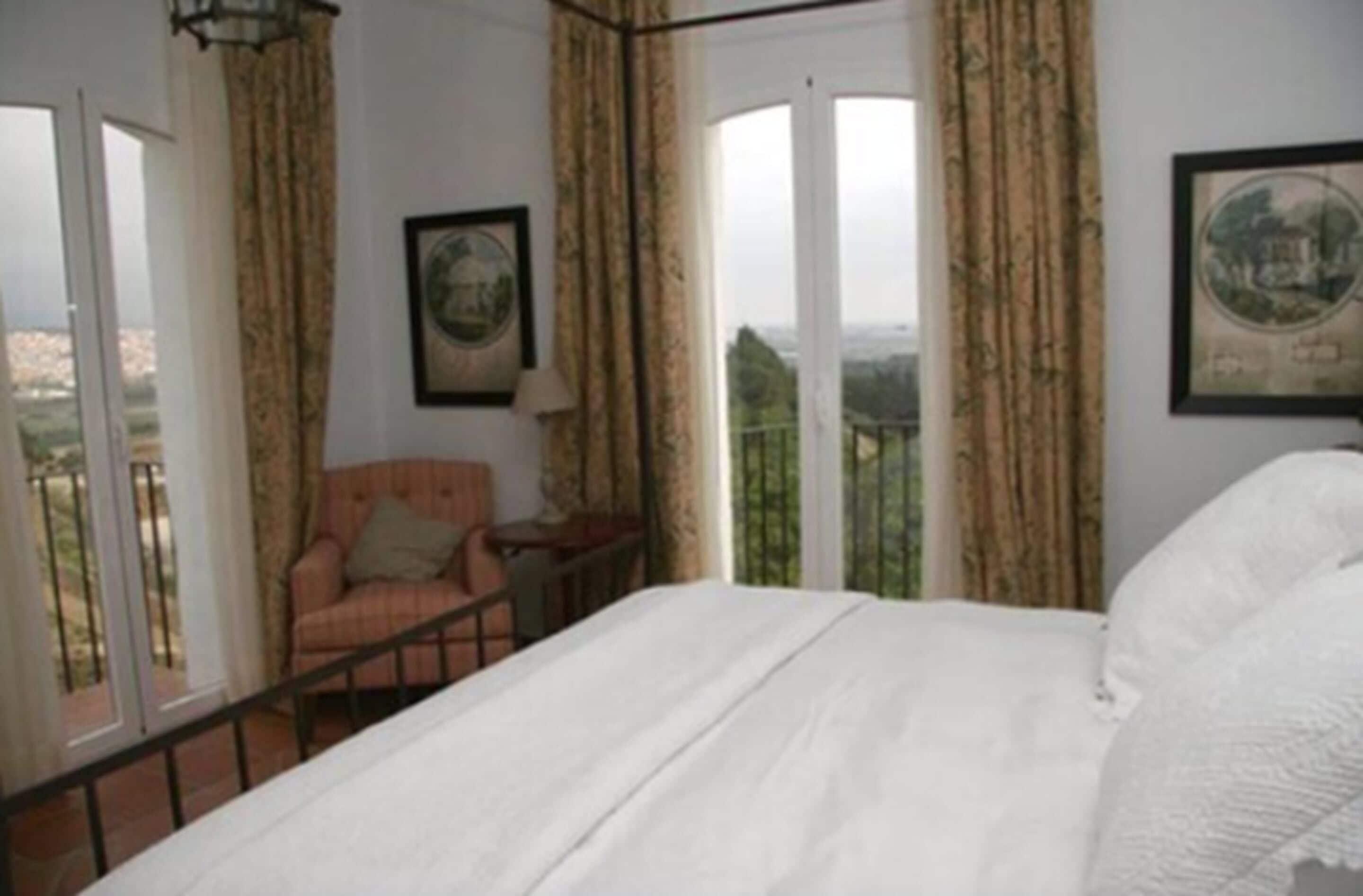 A bedroom with a bed, a chair, and a window with curtains.