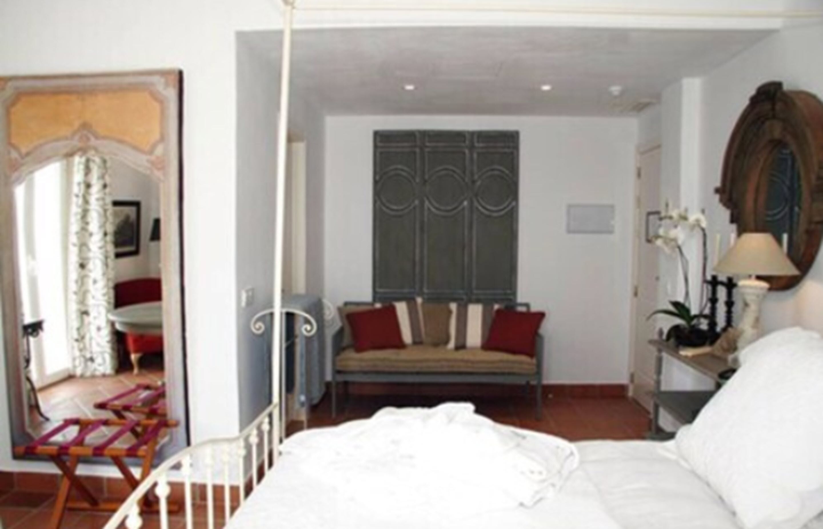 Un dormitorio con cama, sofá, espejo y armario.