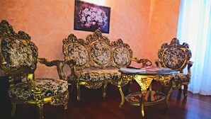 Ein stilvoller Raum mit einer Couch und Sesseln, einem kleinen Tisch und einem gerahmten Bild an der Wand.