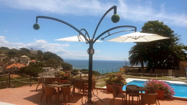 Eine Terrasse mit Sitzgelegenheiten im Freien, einer dekorativen Lampe und Blick auf das Meer.