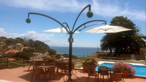 A terrace with outdoor seating, a decorative lamp, and a view of the sea. - Hotel Villa Adele (Celle Ligure)