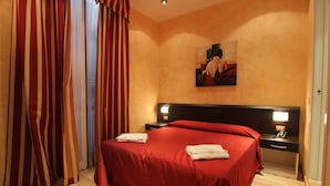 Ein Hotelzimmer mit einem großen Bett, einem Nachttisch, einem Bild an der Wand und Vorhängen.
