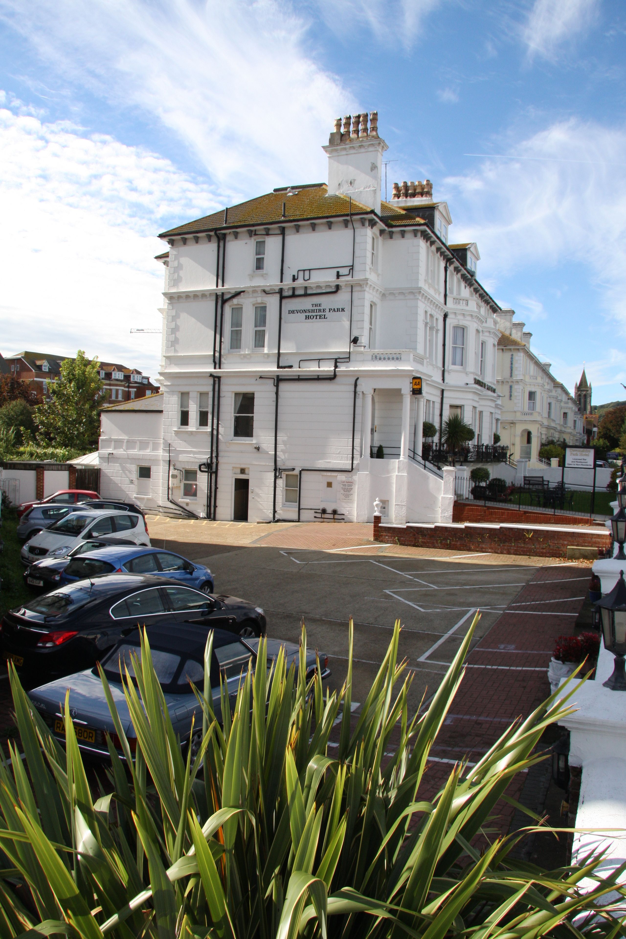 A white building with multiple windows and a sign reading "Devonshire Park Hotel."