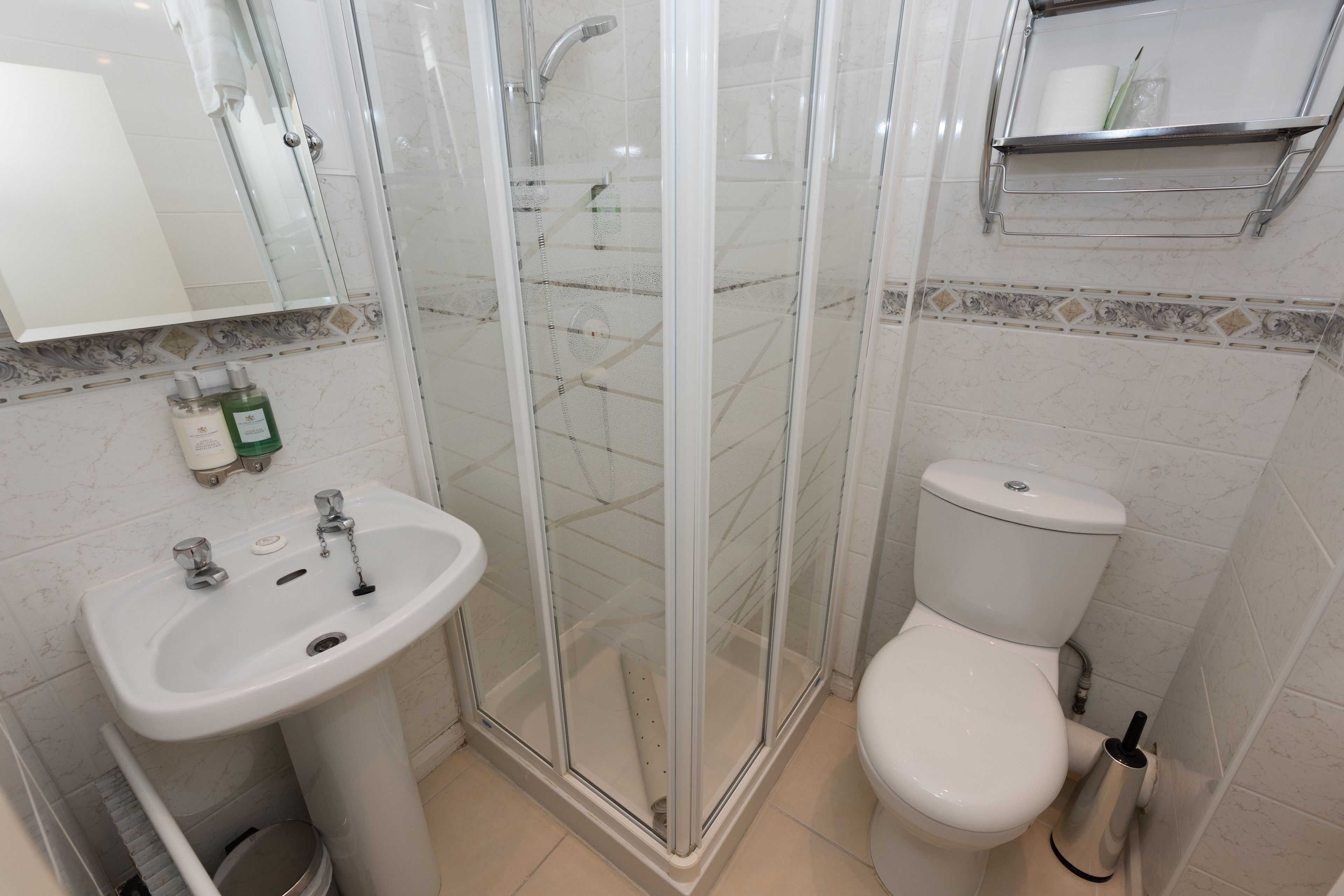 Ein Badezimmer mit einer Duschkabine, einem weißen Waschbecken und einer Toilette.