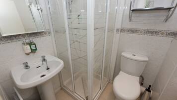A bathroom with a glass-enclosed shower, a white sink, and a toilet.