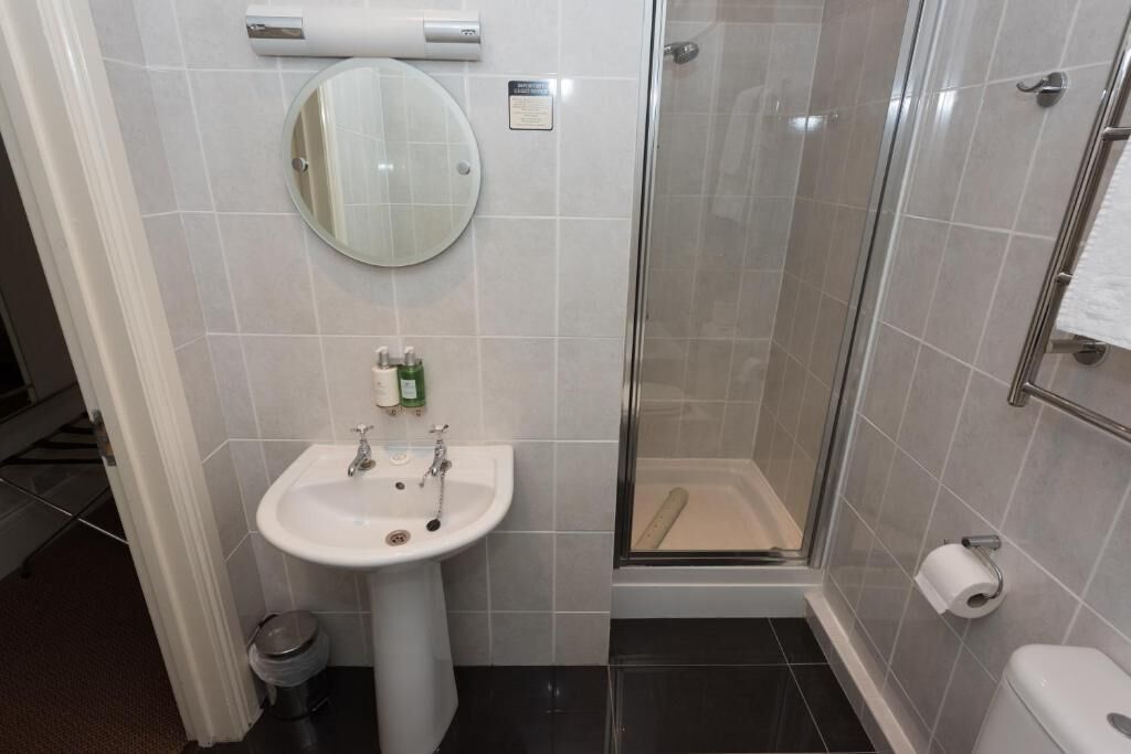 A bathroom with a sink, mirror, toilet, and glass-enclosed shower.
