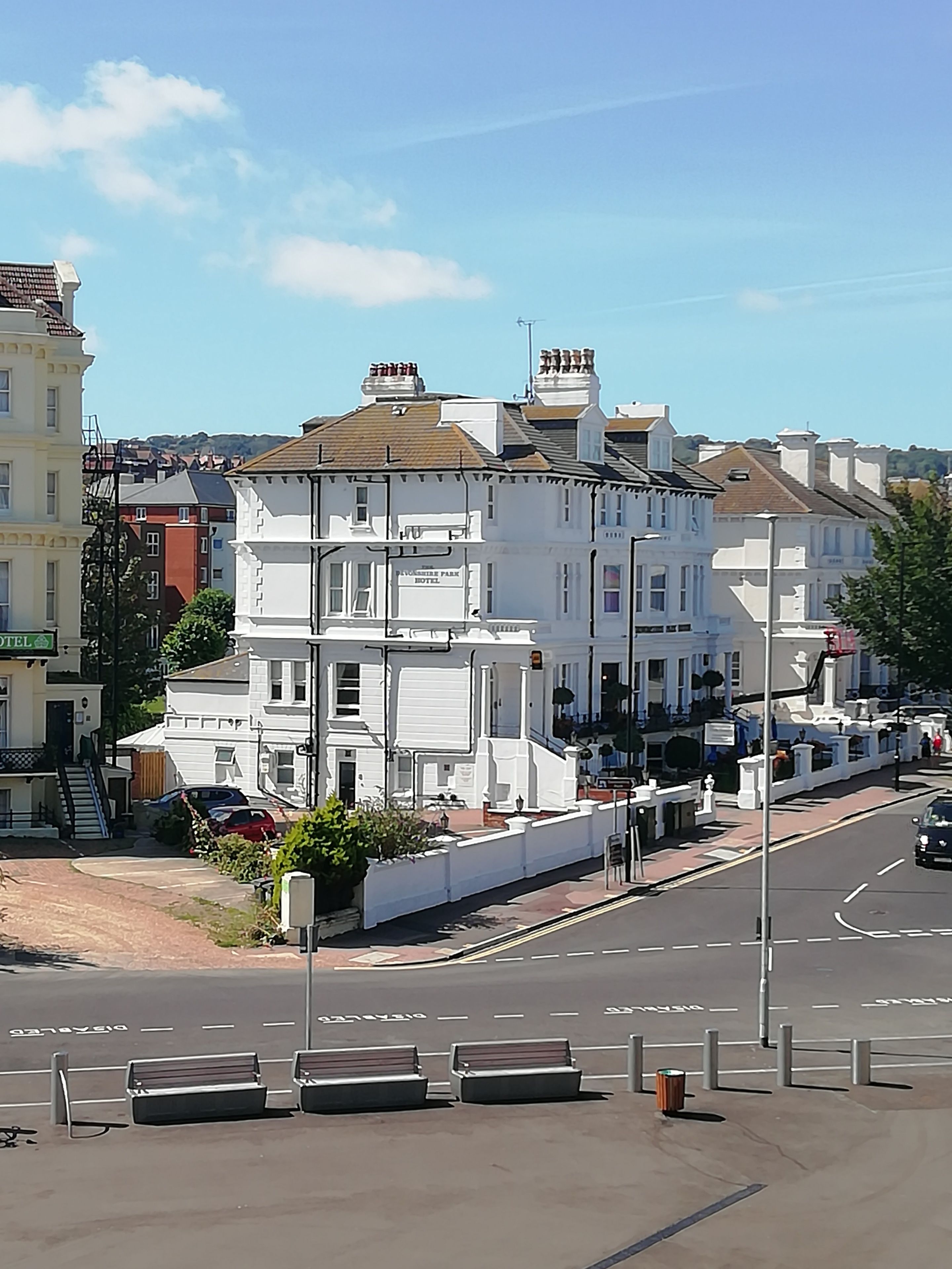 Uma fileira de edifícios brancos com uma placa indicando 'Plymstock Park Hotel'.