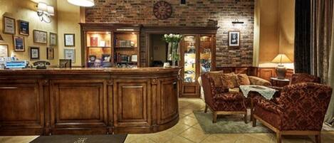 A lobby with a reception desk, a brick wall, a clock, and a sofa.