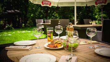 An outdoor dining area with a table set for a meal, surrounded by greenery.