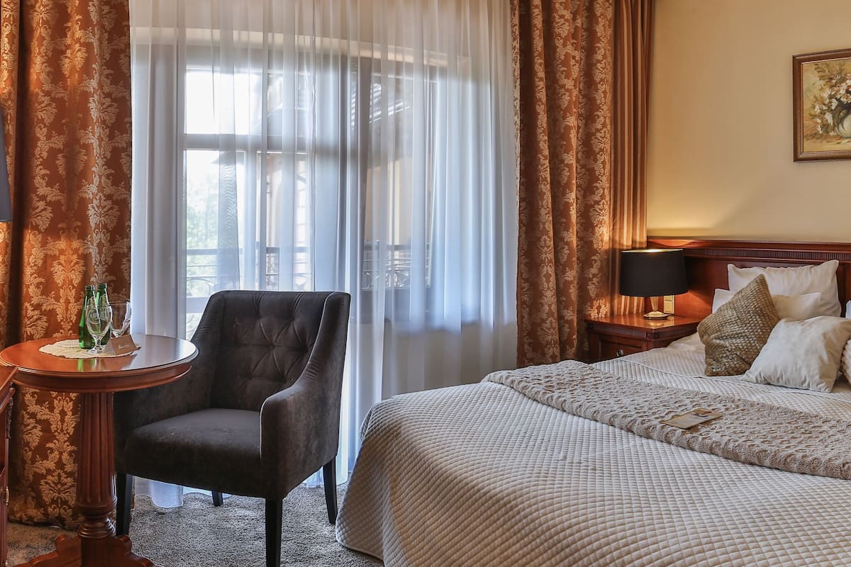 Ein Hotelzimmer mit einem Bett, einem Sessel, einem Schreibtisch und einem Fernseher.
