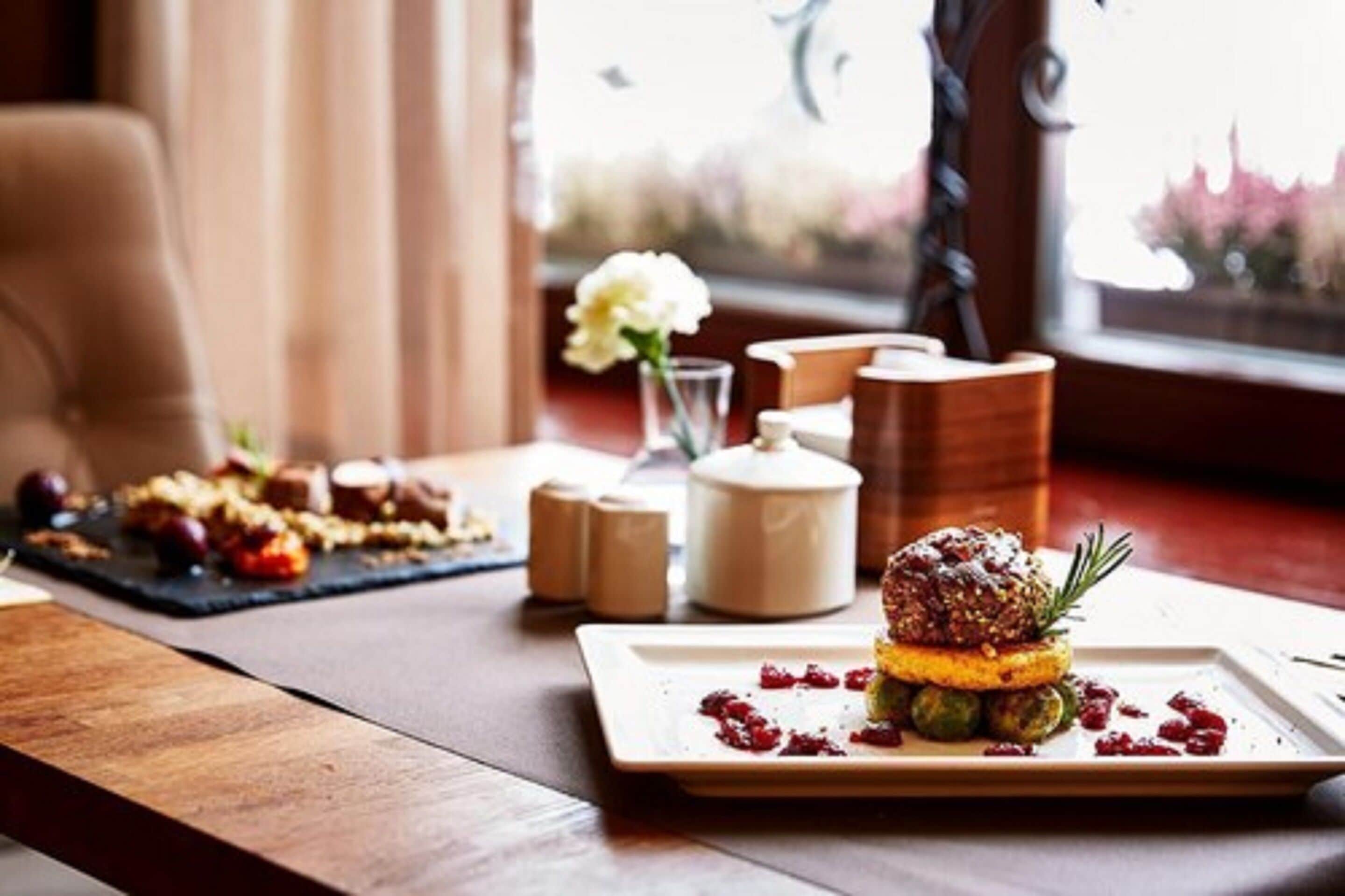 Een eettafel met een bord eten, een vaas met een bloem, zout- en peperstel, en een kandelaar.