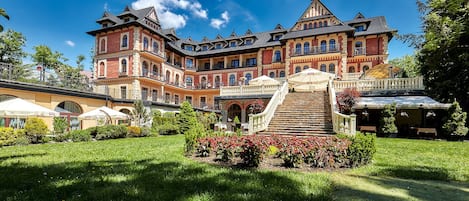 Un edificio grande e histórico con un patio central, una escalera y un jardín bien cuidado.