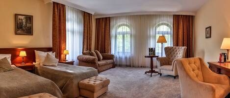 A hotel room with two beds, a sofa, a chair, and a small table.