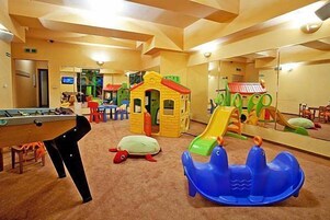 Un área de juegos infantiles con mesa de billar, una casita y un tobogán.