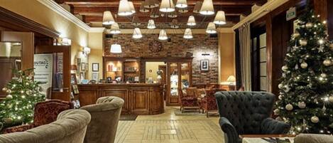 A lobby with a wooden ceiling, a Christmas tree, and a reception desk.