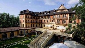 Un hotel imponente con un patio, varios balcones y una escalera central.