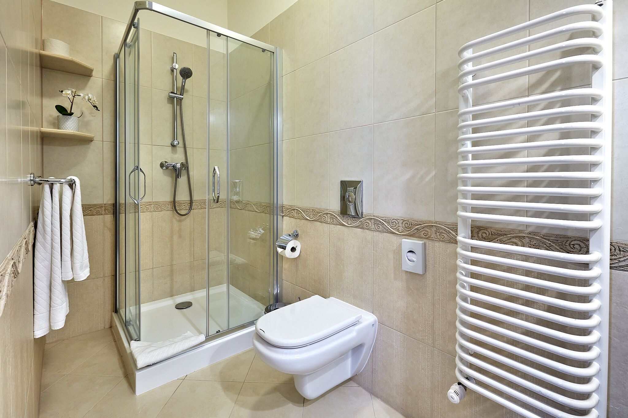 Un baño con ducha de vidrio, inodoro y perchero para toallas.