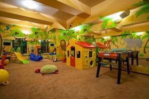 Een speelkamer met een glijbaan, een poppenhuis en diverse speelgoed.