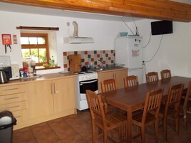 Cocina compacta con estufa, lavamanos y mesa de comedor con sillas.