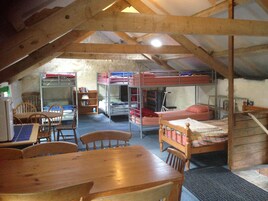 Un dormitorio con literas, una mesa de madera, sillas y una estantería.