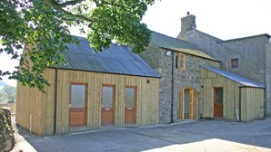 A rustic building with a stone facade and wooden exterior, featuring multiple doors and windows. - Greencarts Bunkhouse (Hexham)
