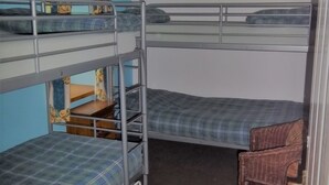 A bunk bed room with a blue wall, a wooden chair, and a hanging light fixture. - Greencarts Bunkhouse (Hexham)