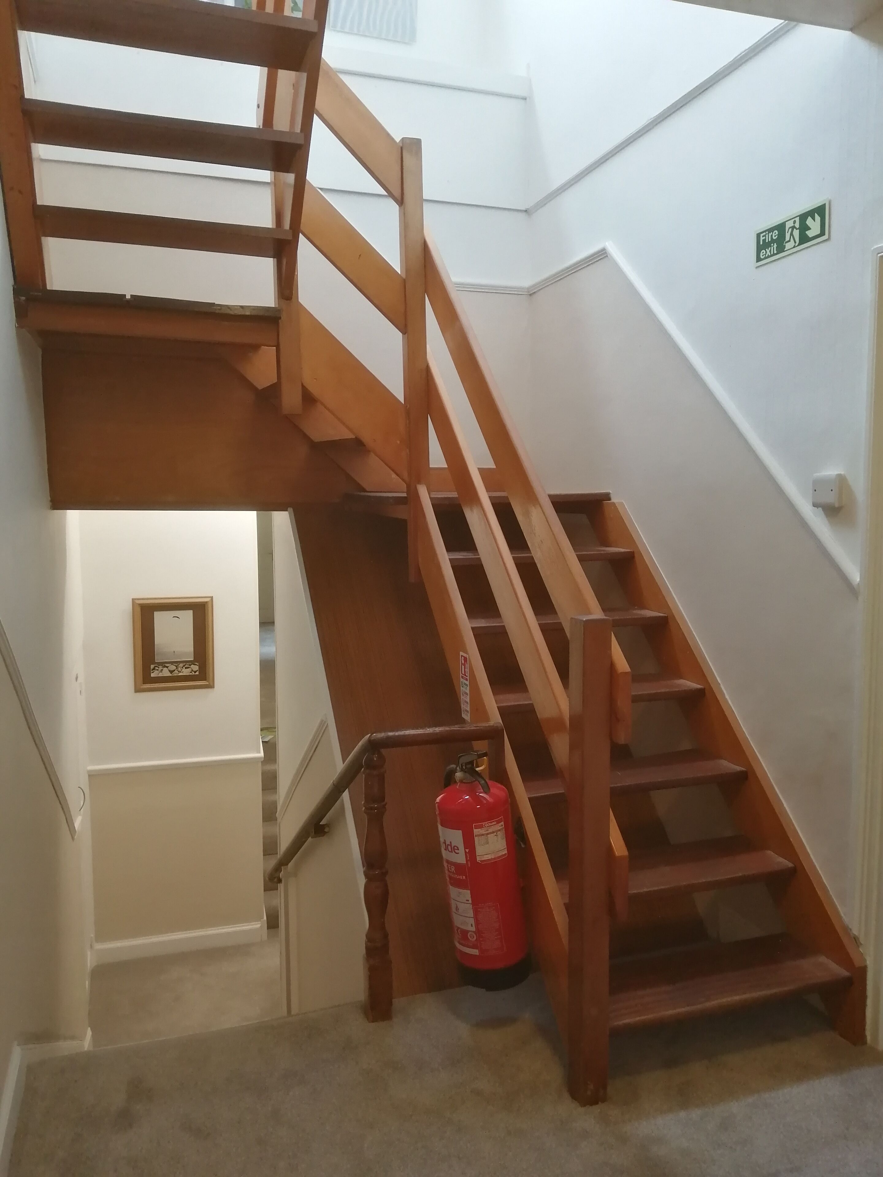 Una scala in legno con un estintore fissato alla parete.