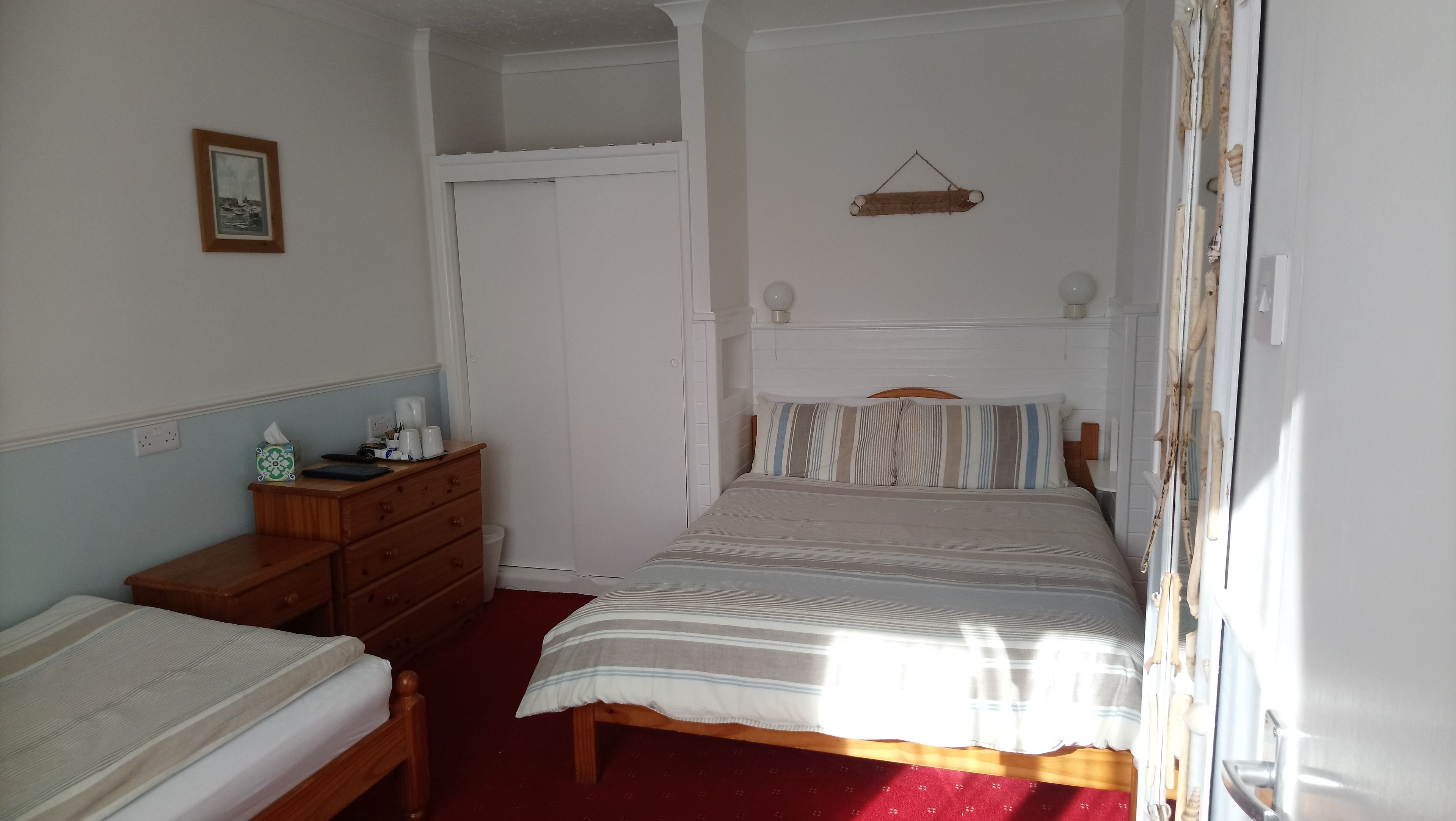 A bedroom with a bed, a dresser, a nightstand, and a framed picture on the wall.